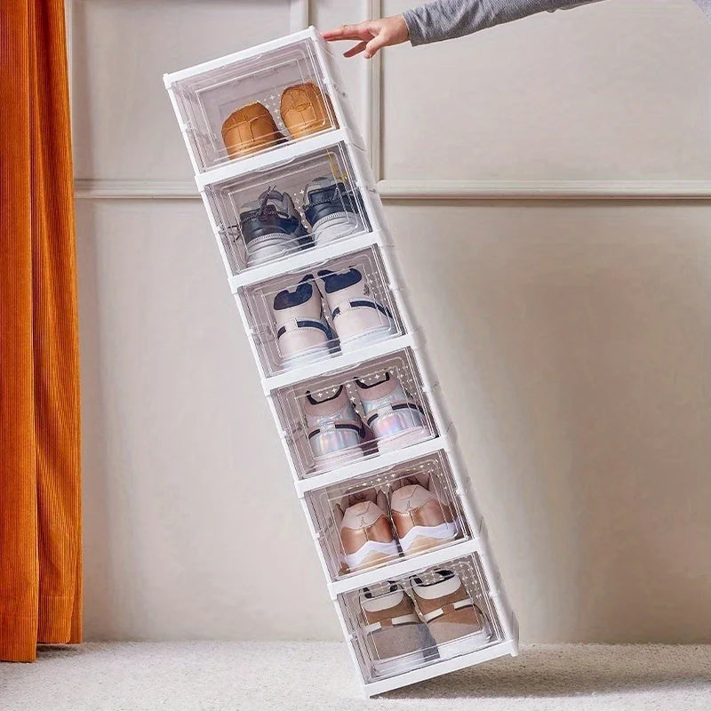 Stack of white shoe organizer boxes being tilted, showing multiple pairs of shoes inside clear doors