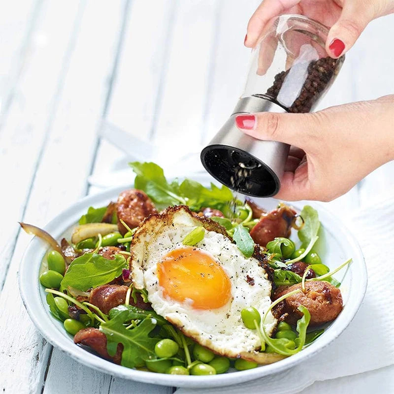 hand using pepper grinder to season a plate of food with egg and vegetables