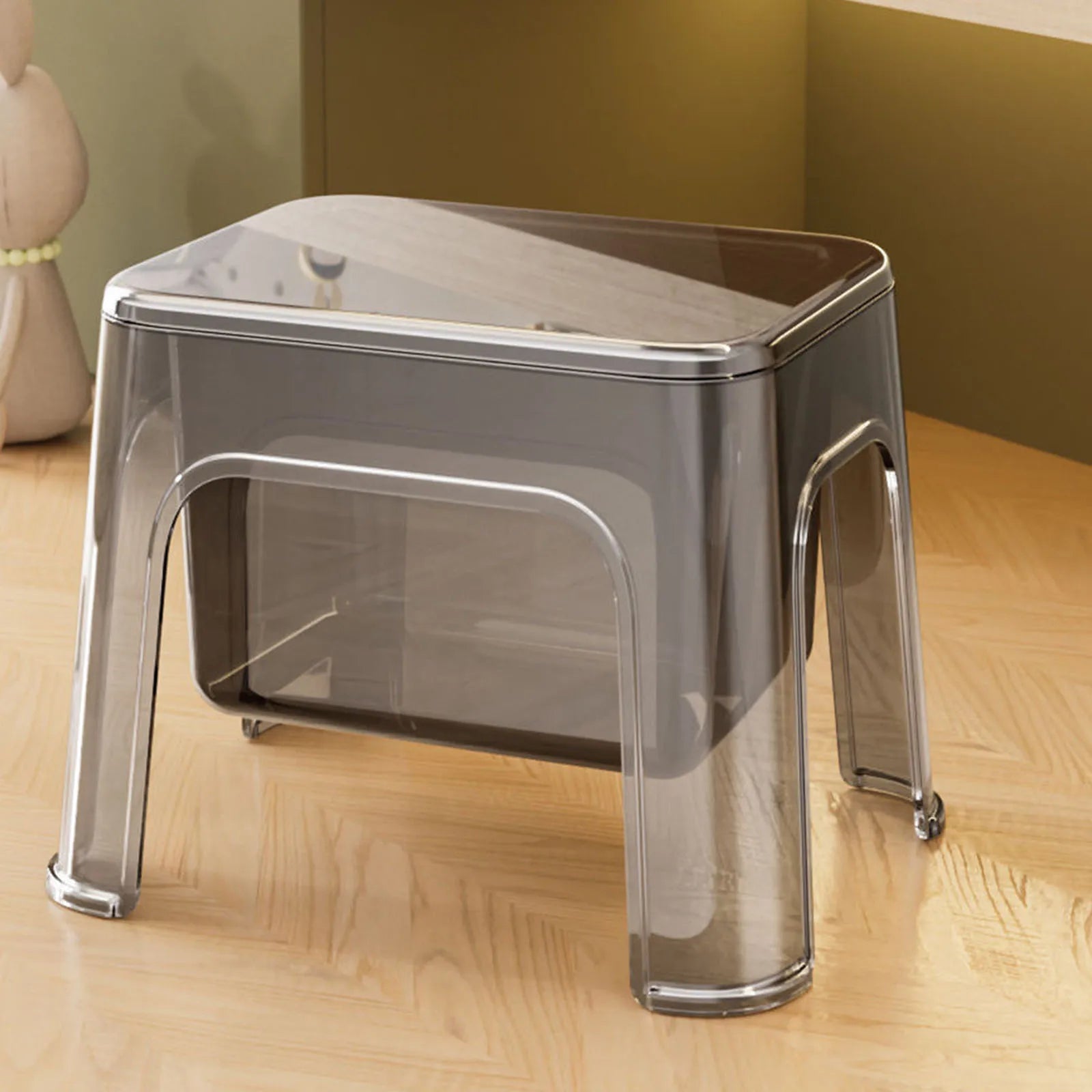 Gray transparent step stool with lid in a home setting on wood floor