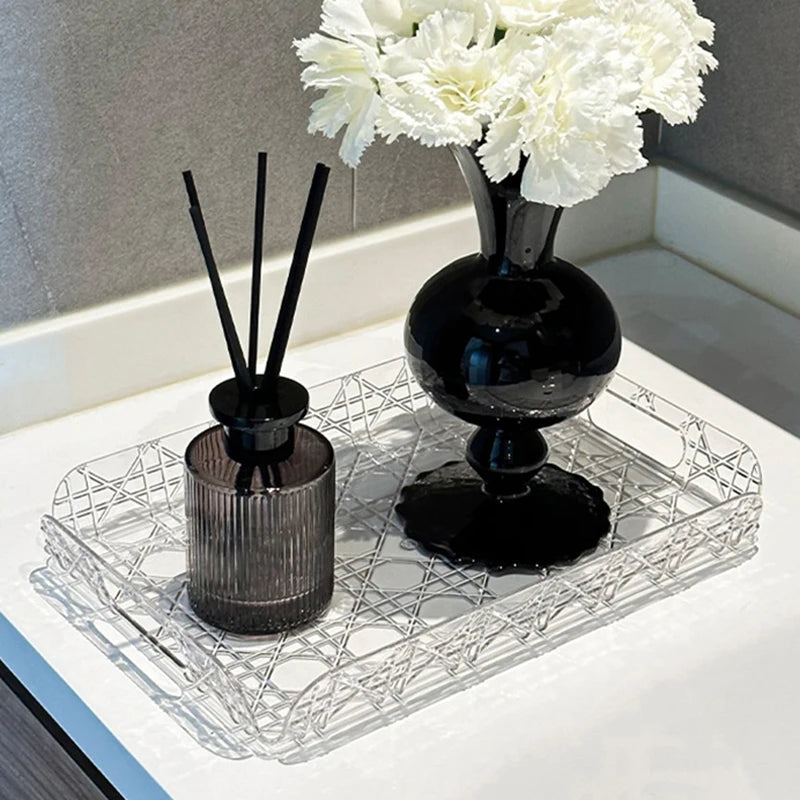 Clear tray on a bathroom counter, styled with a black vase of white flowers and a diffuser.