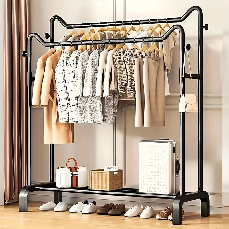 Freestanding black double rail clothes rack in a bedroom, displaying jackets, shirts, bags, and shoes