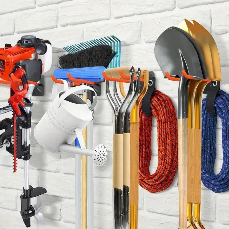 Garage wall with mounted double hooks holding a variety of garden tools, brooms, and hoses