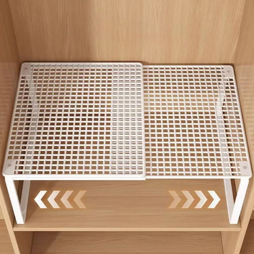 White adjustable mesh steel shelf divider expanded on a wooden closet shelf, viewed from above
