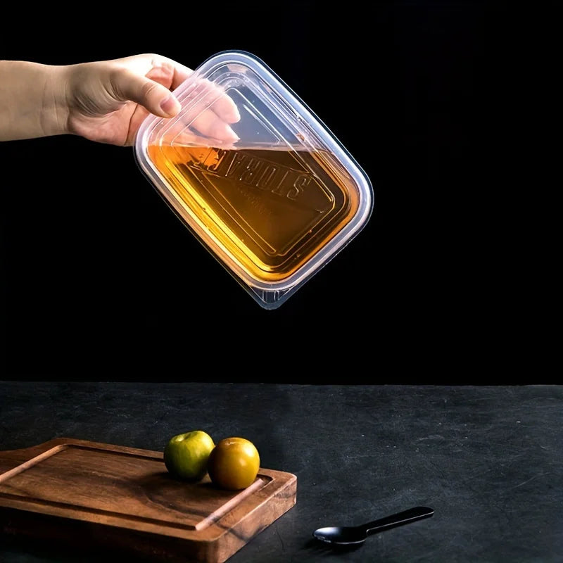 Hand holding a clear plastic food storage container with liquid inside against a black background