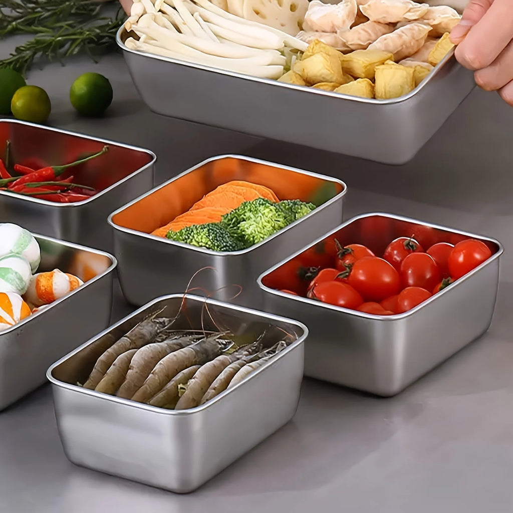 Selection of stainless steel food containers holding fresh vegetables and seafood