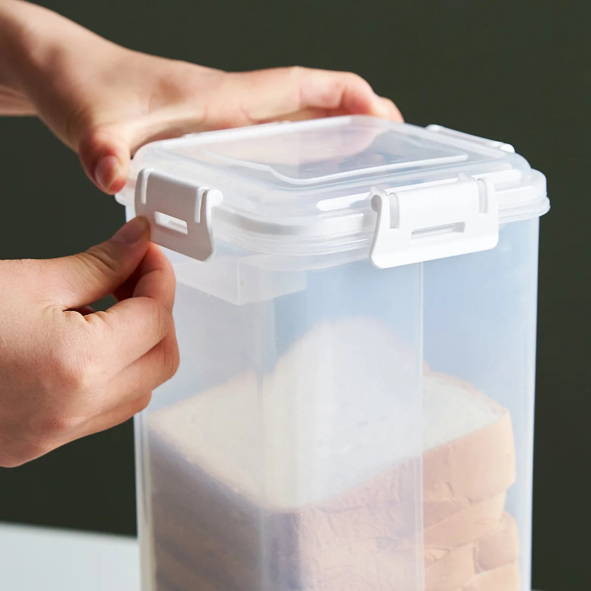 hands fastening white locking clips on clear bread container lid