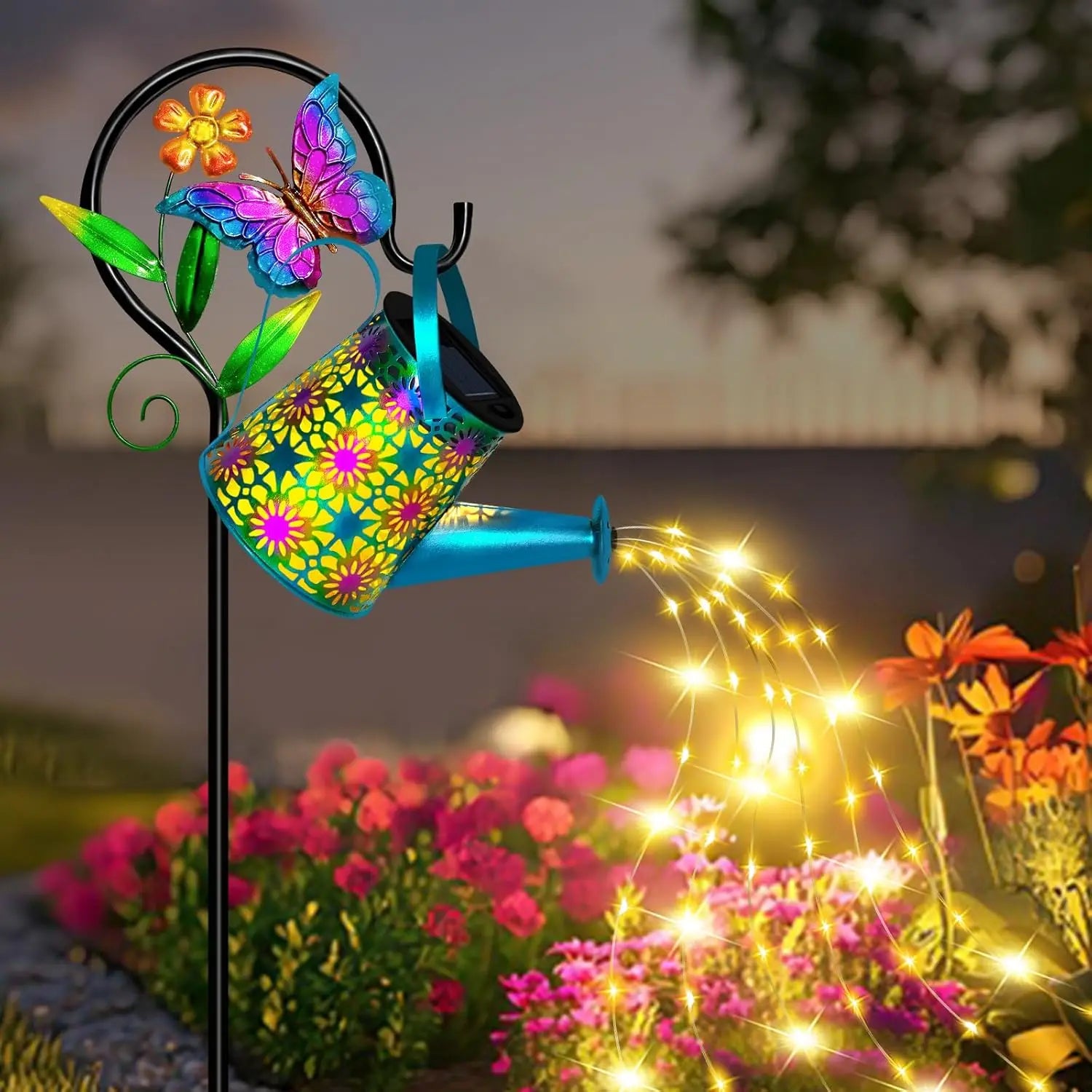 Solar butterfly watering can lantern glowing at night, lighting up a garden bed with bright fairy lights and colorful metal butterfly details.