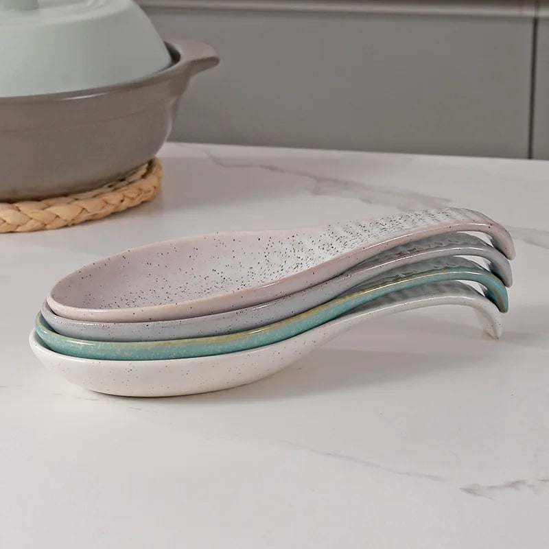 Stacked speckled ceramic spoon rests showing nesting design on kitchen counter