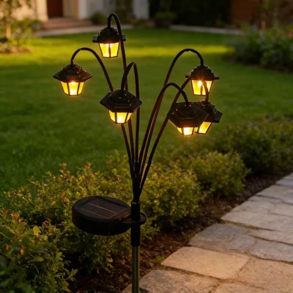 Solar-powered lantern stake light with six heads along a garden path at dusk
