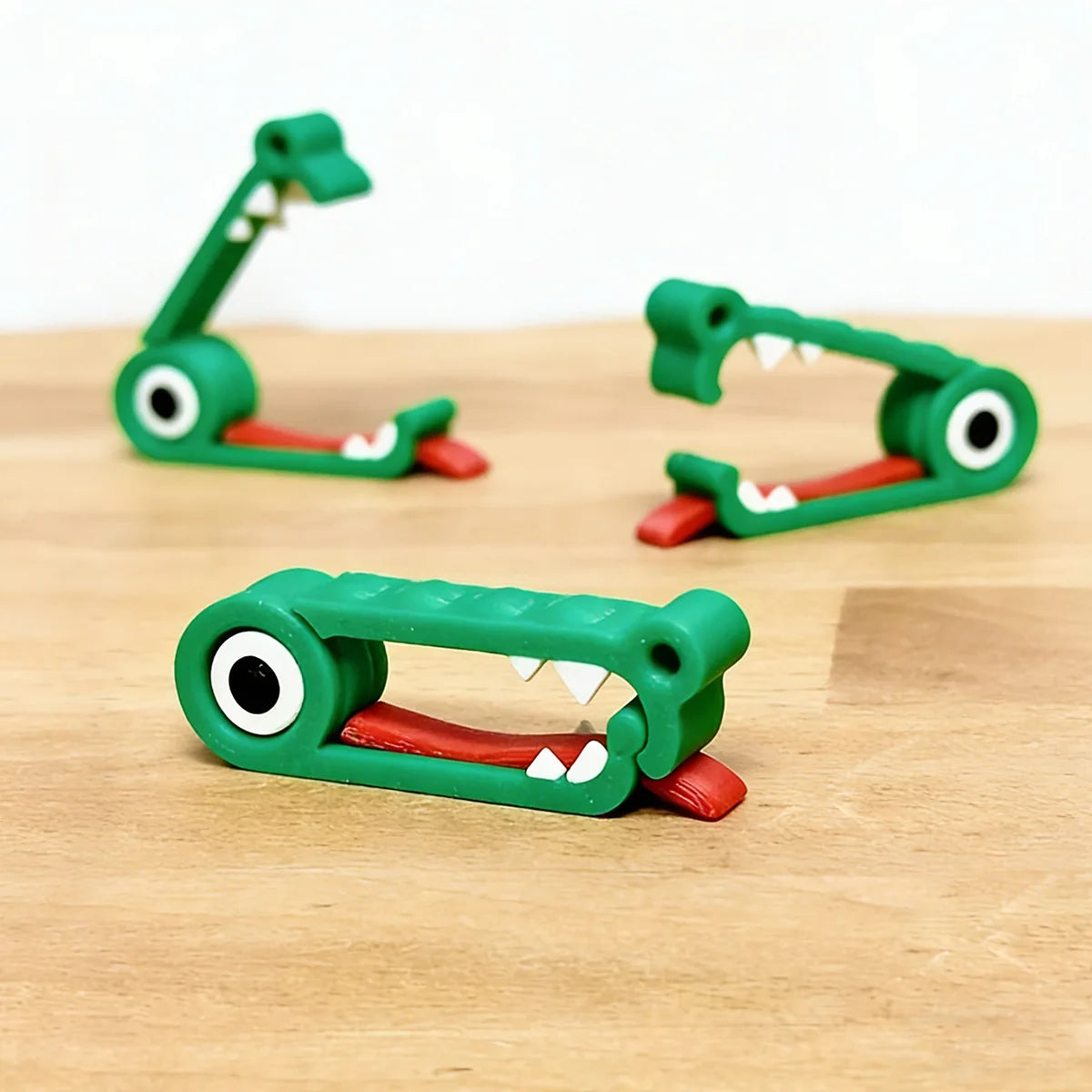 Three crocodile cable organizer clips on wood, two open and one closed