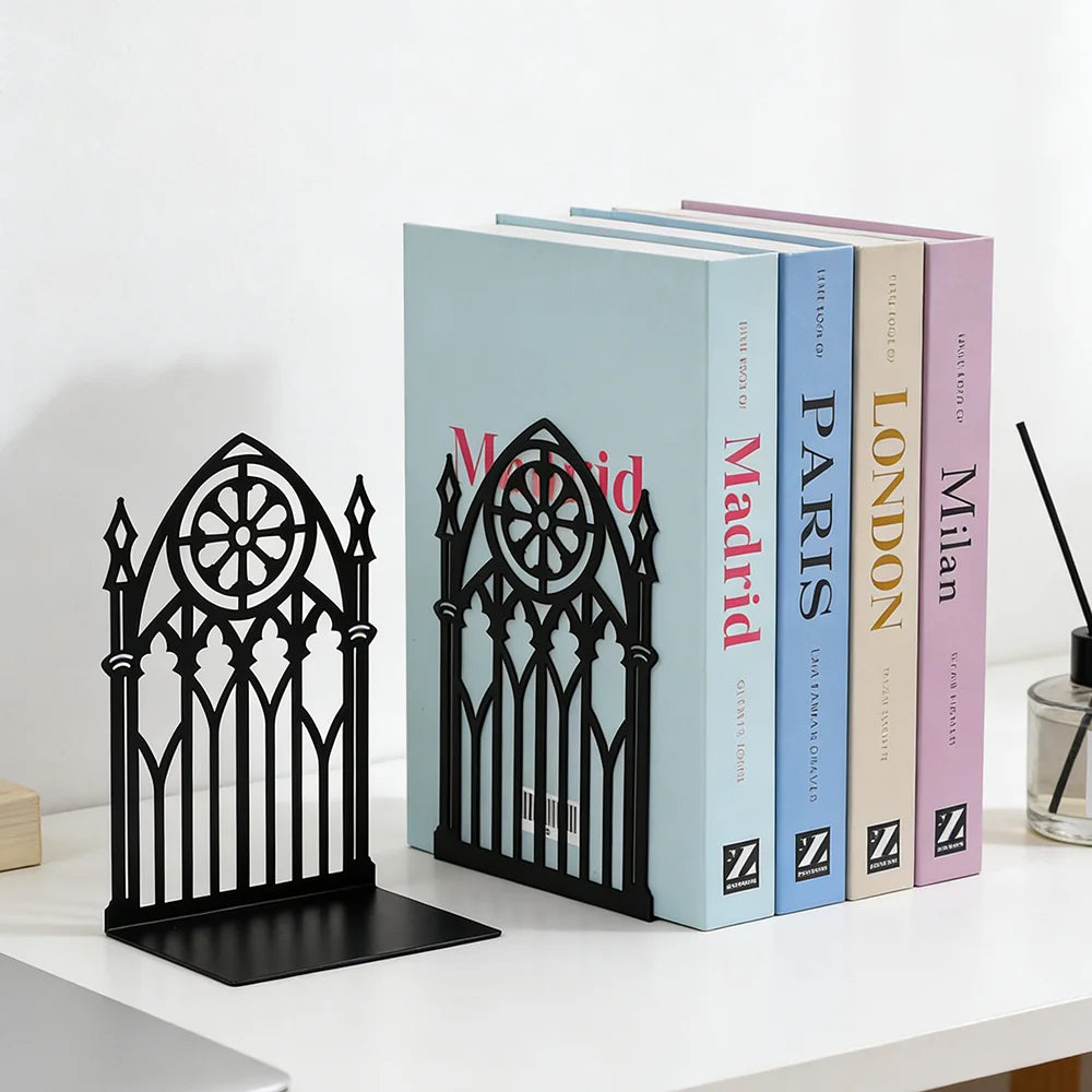 Black gothic metal bookends holding pastel-colored books on a white desk