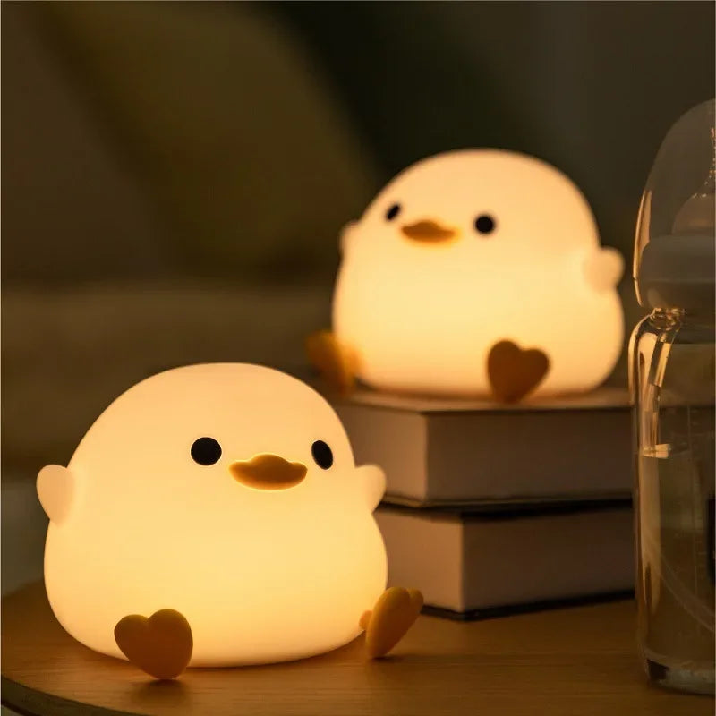 Soft silicone duck night light glowing on a bedside table and stacked books