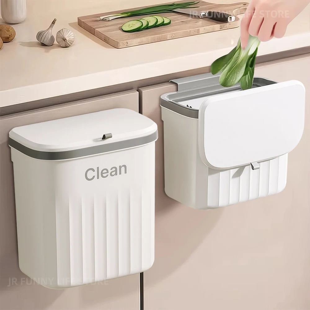 Two hanging trash cans with lids mounted on a kitchen cabinet door, one with an open lid as food scraps are tossed in
