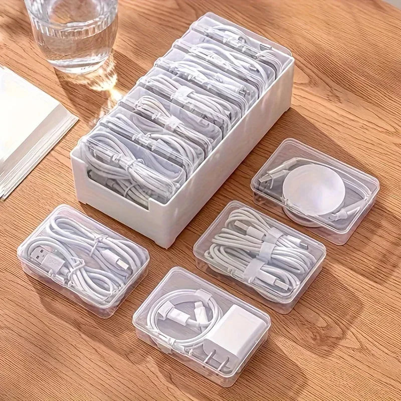 White cable organizer box with clear compartments, several removed and filled with cords, on a wood surface