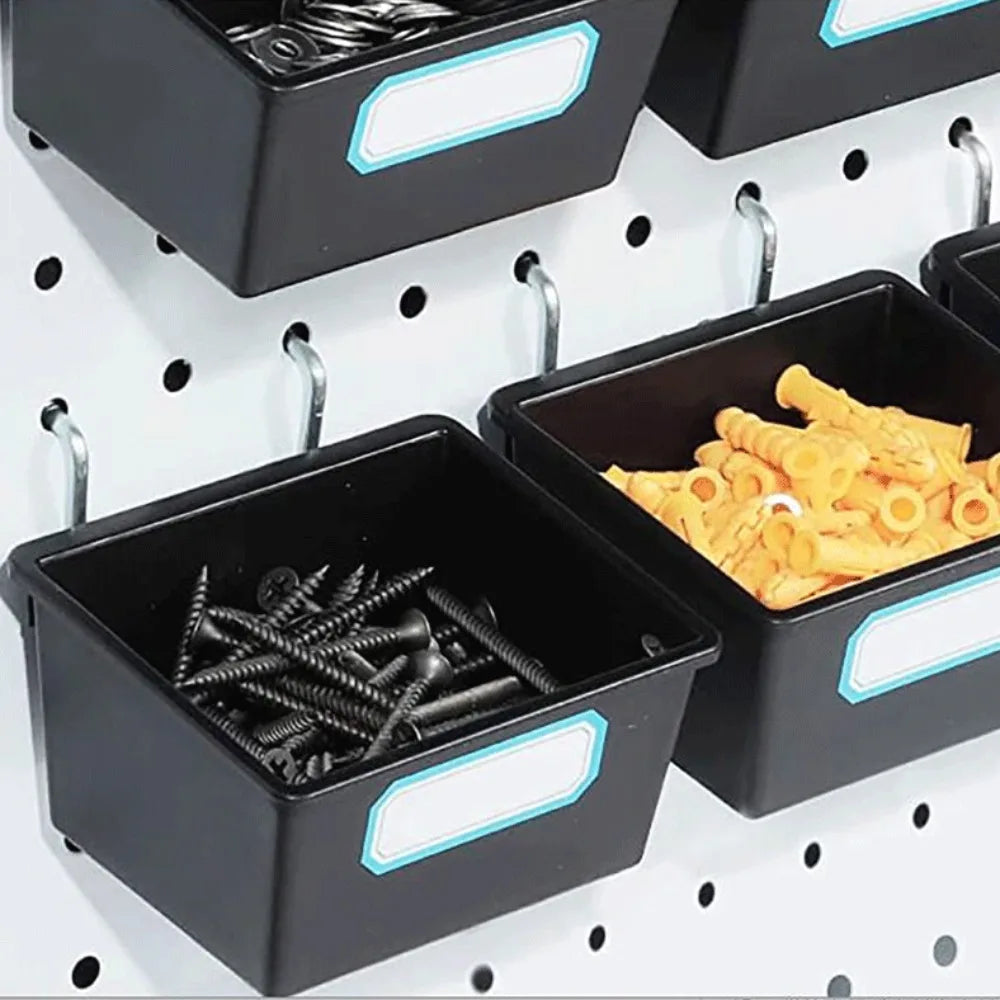 Close-up of two black pegboard bins with writable labels, attached to a white pegboard and filled with screws and yellow anchors