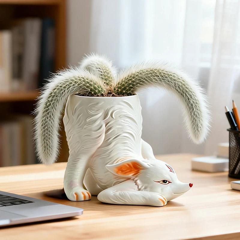 Fox resin planter holding a fuzzy cactus on a wooden desk in front of a bookshelf