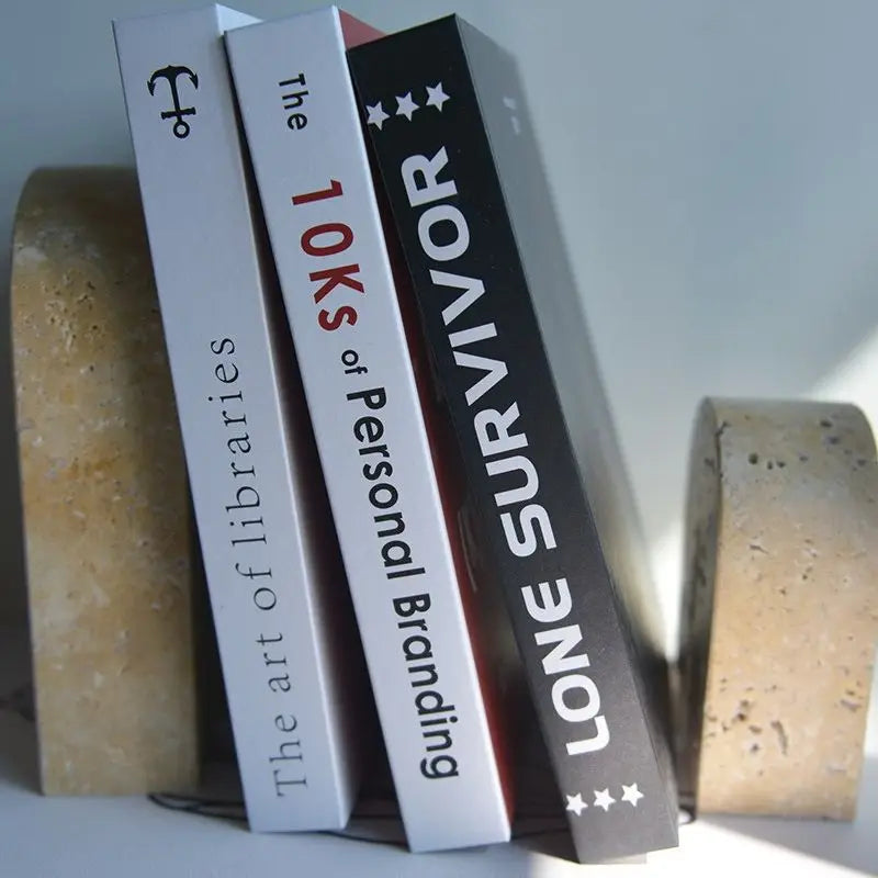 Close-up of beige travertine stone bookends supporting books at an angle, showing natural texture