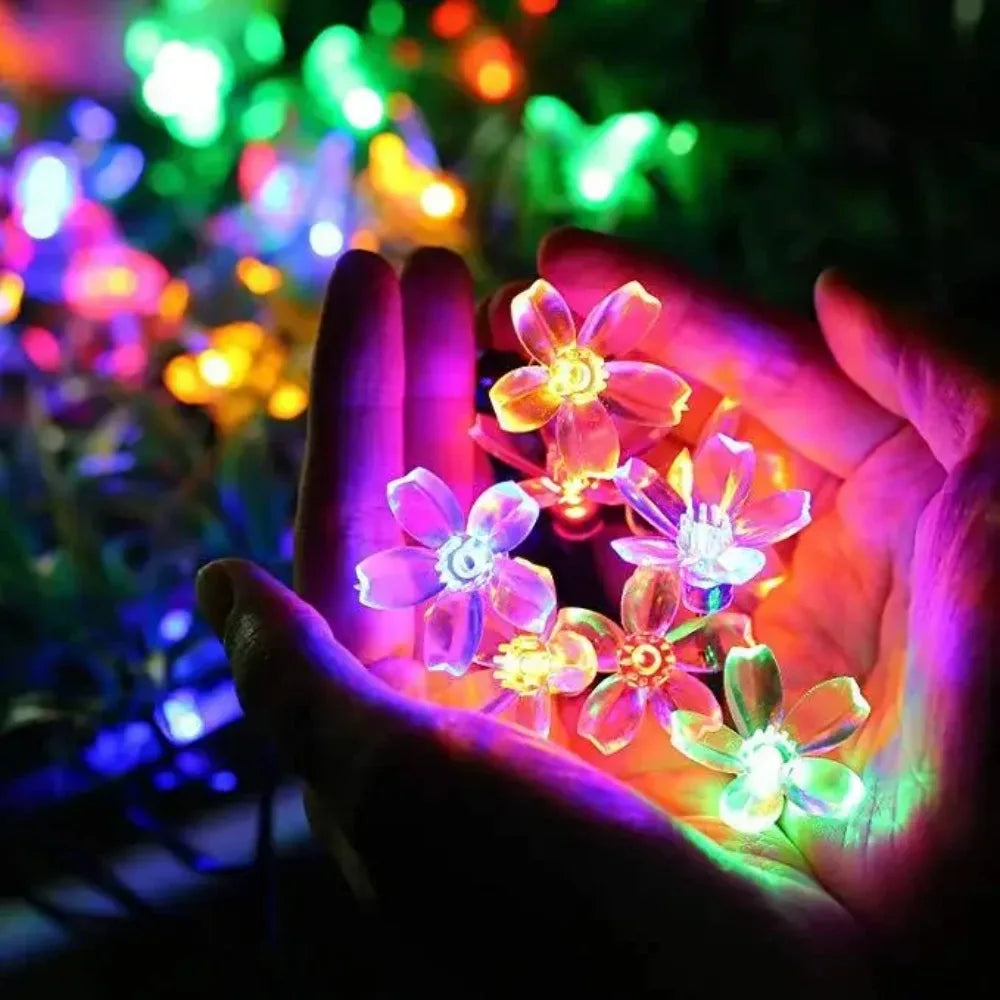 Multicolor LED cherry blossom string lights displayed in hands with glowing floral effect