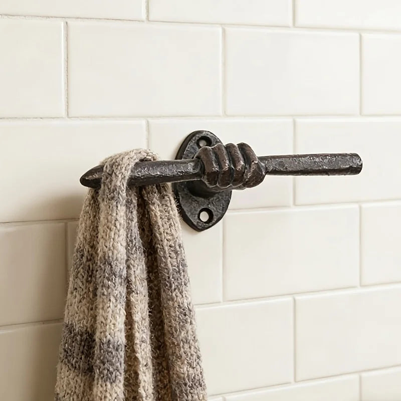 Cast iron hand wall hook on tiled bathroom wall holding a striped towel