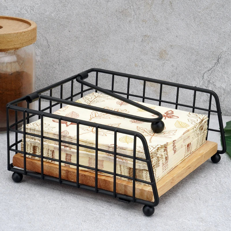 Metal and wood napkin holder holding leaf-printed napkins on a table