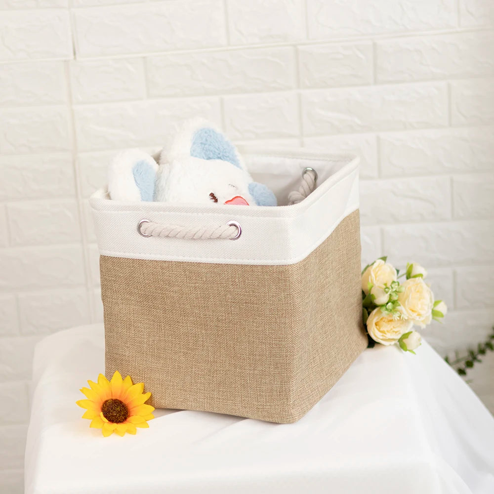 Khaki fabric storage basket with sturdy rope handles, shown with plush toy and floral arrangement for shelf or closet use