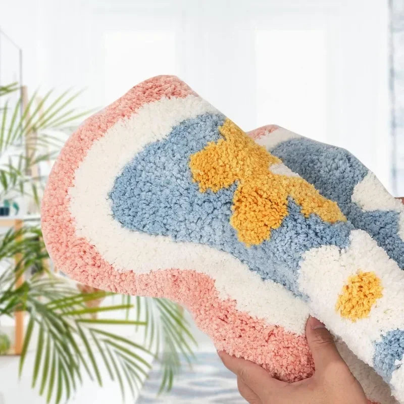Close-up of a colorful pink, blue, and yellow flower-patterned faux wool mat being held up to show texture.