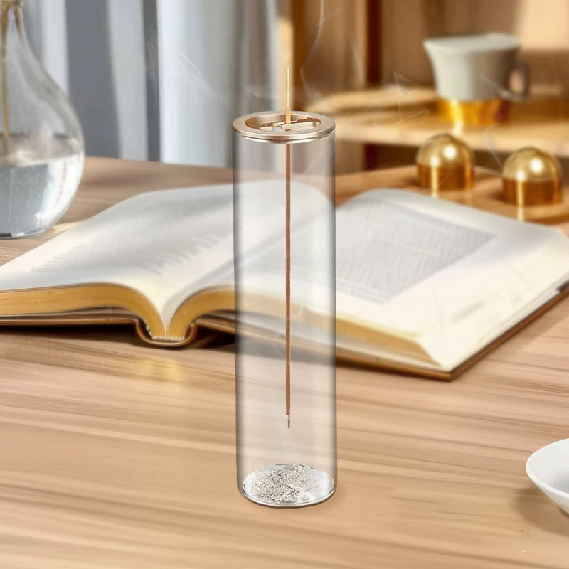 Glass incense holder placed on a wooden table in a living space with a book