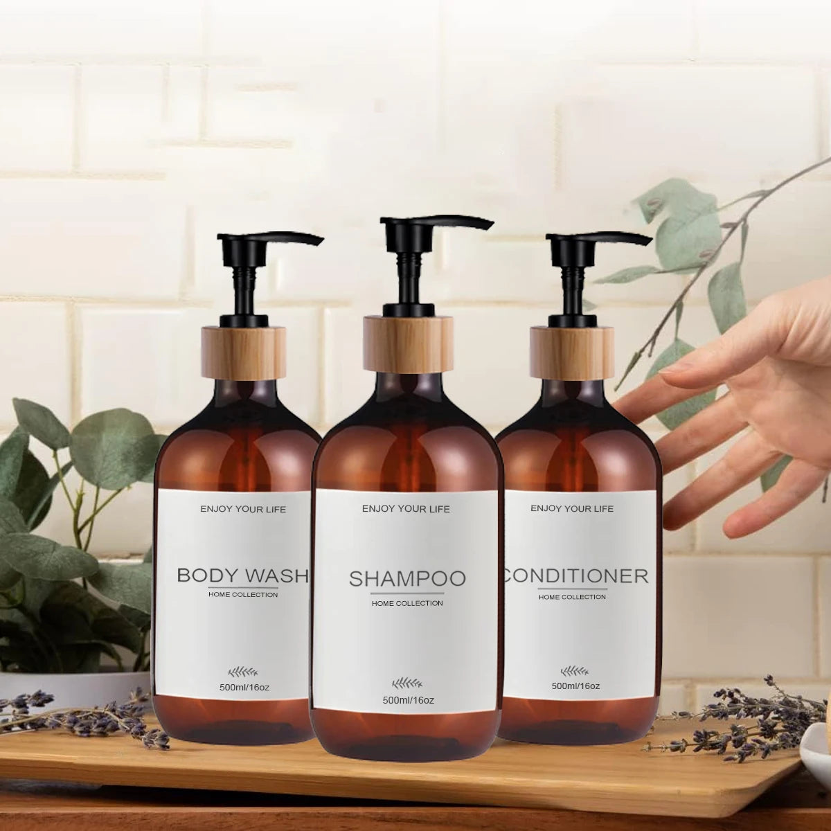 Amber plastic shampoo, conditioner, and body wash dispenser bottles with pump tops on a bathroom counter with hand reaching