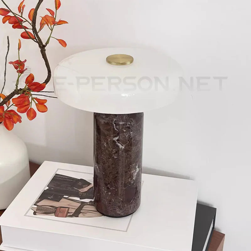 Marble base lamp on white stack of books with vase and orange flowers