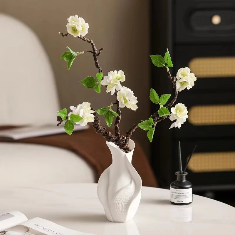 white ceramic vase on table holding flowering branches in living room