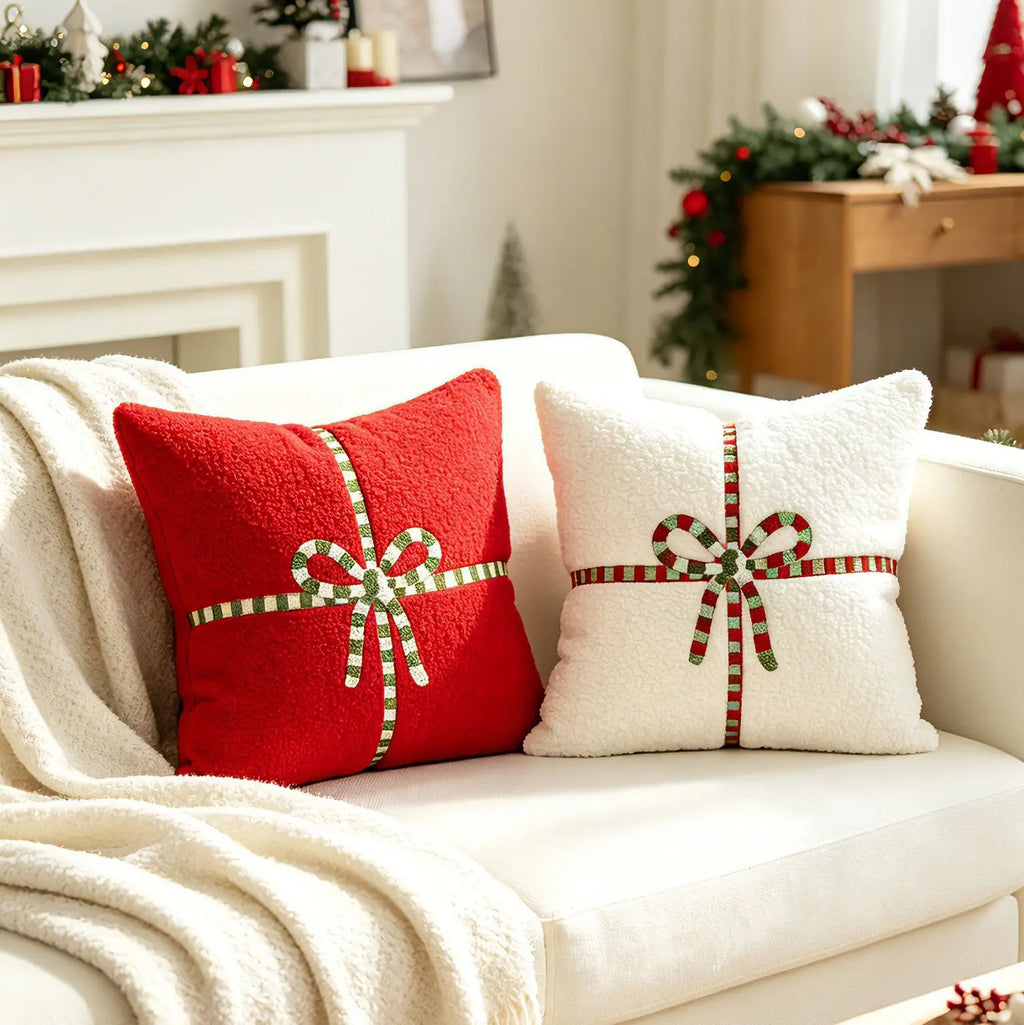 Red and white square gift bow teddy velvet pillow covers on a neutral sofa with cozy holiday decor