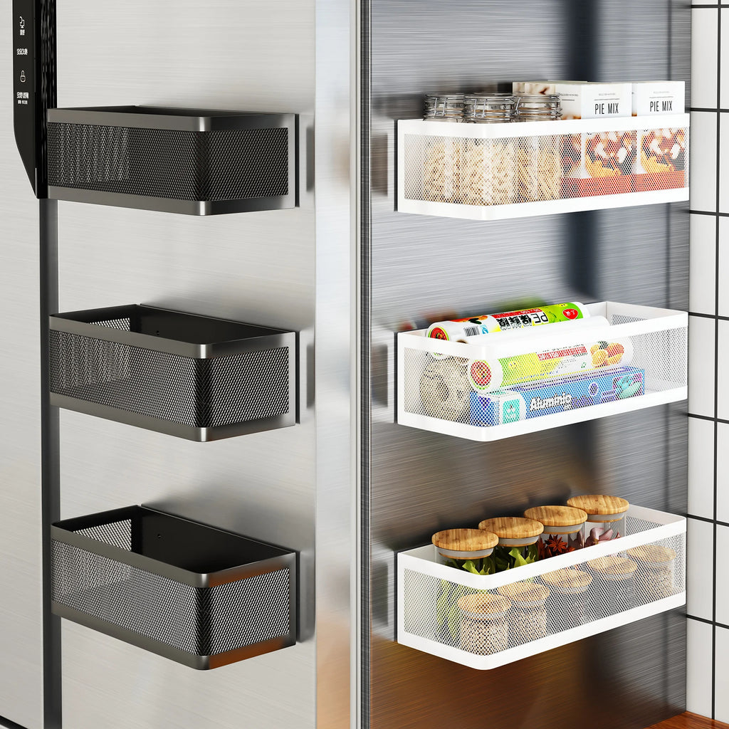 Black and white magnetic metal storage baskets attached to a refrigerator, holding jars, snack boxes, and wraps.