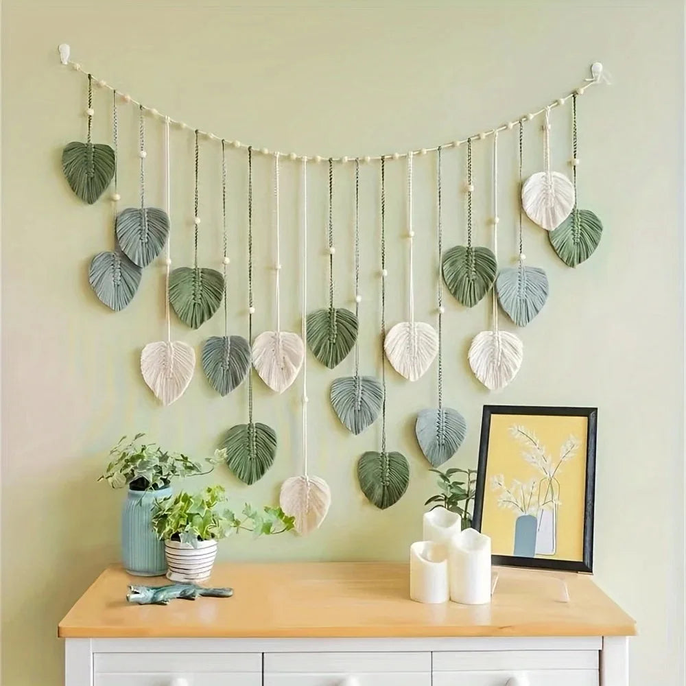 Leaf macrame wall hanging displayed above a dresser with plants and candles