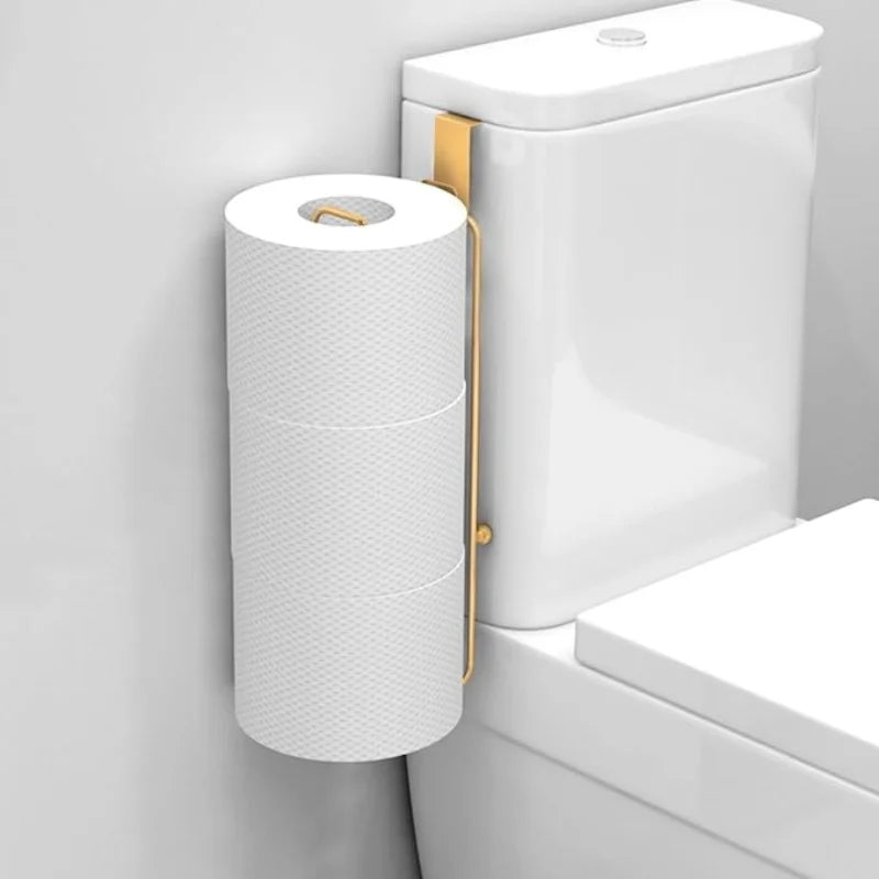 Golden metal toilet paper holder hanging over a white toilet tank, holding extra toilet paper rolls