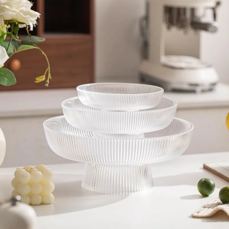 Set of three ribbed glass pedestal bowls nested on a white countertop