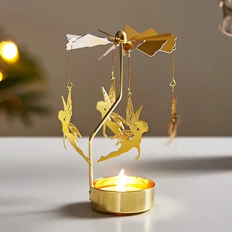 Gold rotating tealight candle holder with fairy charms spinning above a lit candle on a white tabletop