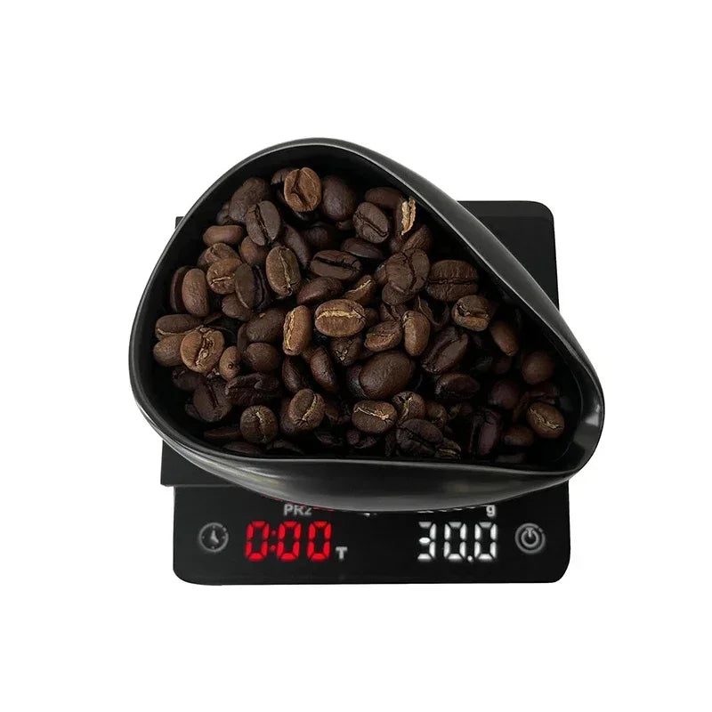 Black ceramic tray holding coffee beans on a digital scale