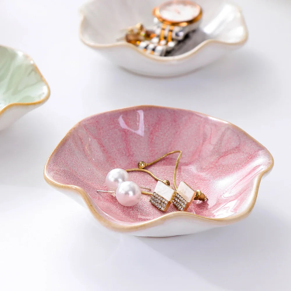 Pink ceramic petal jewelry tray on white surface, with jewelry inside and additional trays visible