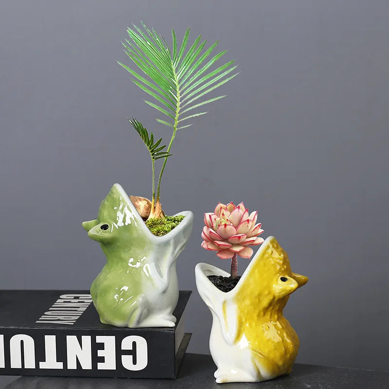Green and yellow frog-shaped ceramic animal planters with small indoor plants