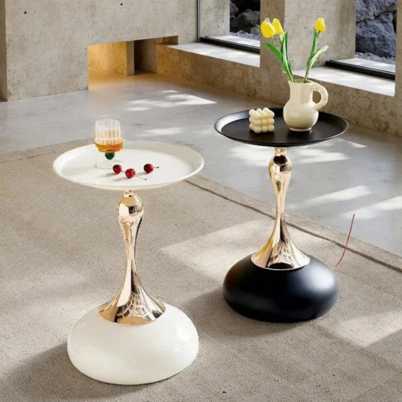 Black and white round side tables with gold stems, styled with drinks and decor in a bright room