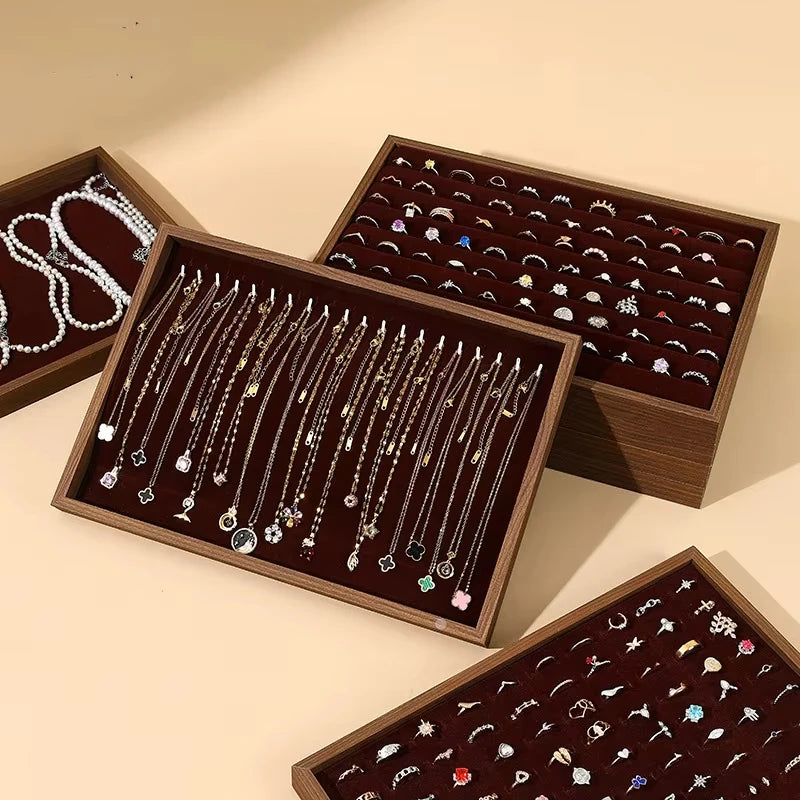 Wooden jewelry trays displaying rings, necklaces, and bracelets in organized sections