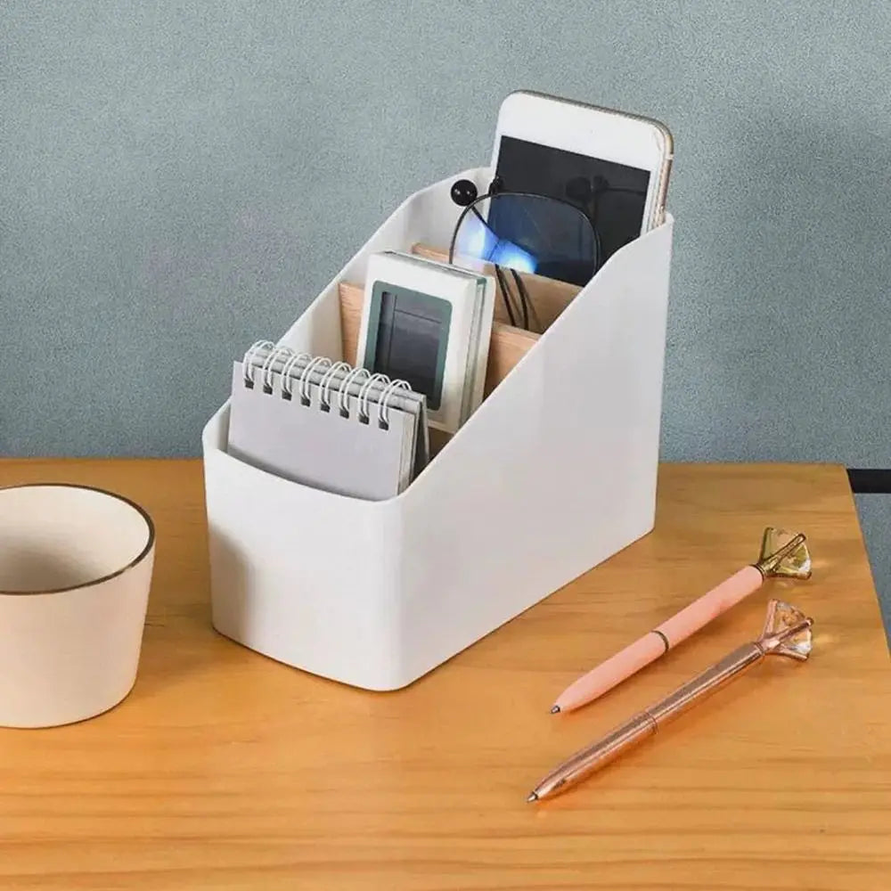White tiered organizer with wood dividers on a wooden table, holding a phone, notepad, and glasses