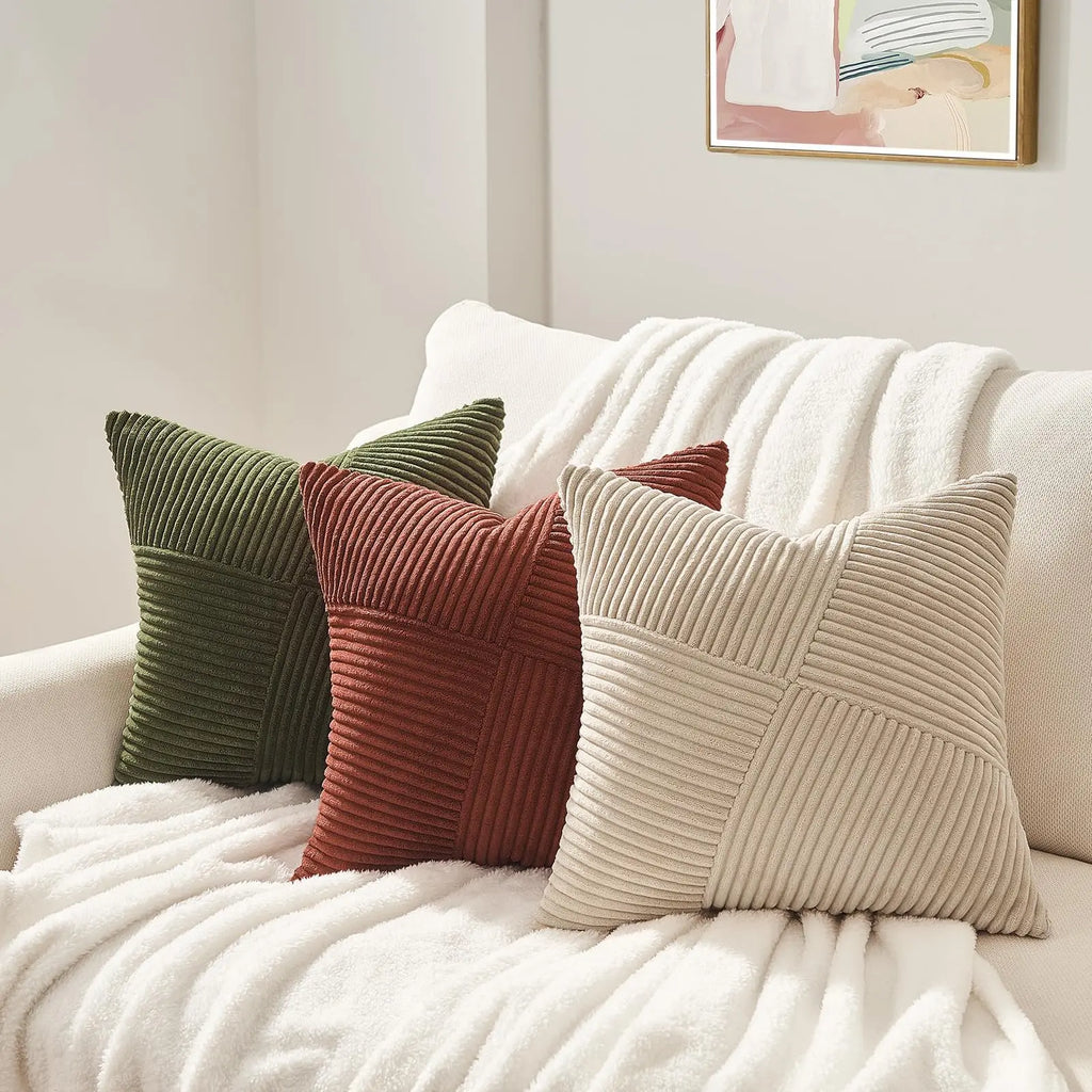 Green, rust, and beige corduroy pillow covers arranged on a cream sofa