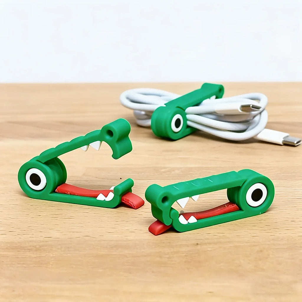 Two crocodile cable organizers on the table with a coiled USB cable in the background
