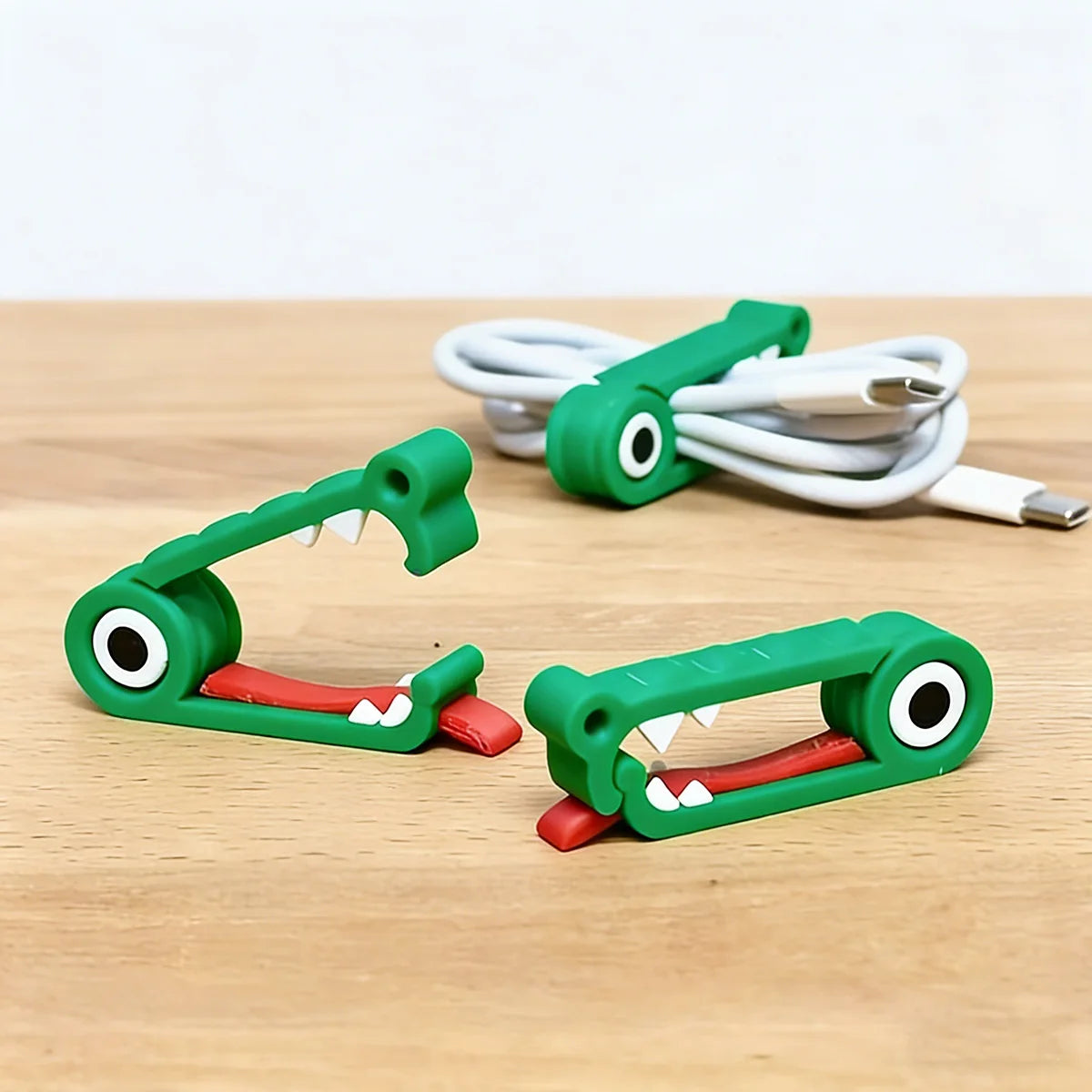 Two crocodile cable organizers on the table with a coiled USB cable in the background