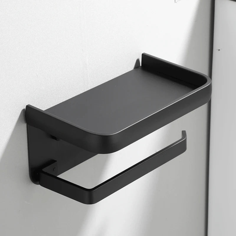 Simple black aluminum wall-mounted toilet paper holder with empty tray, mounted on a plain wall.