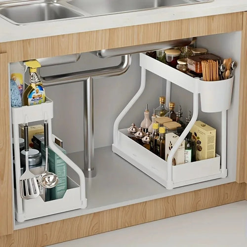 White 2-tier under sink organizer in kitchen cabinet holding cleaning supplies and utensils