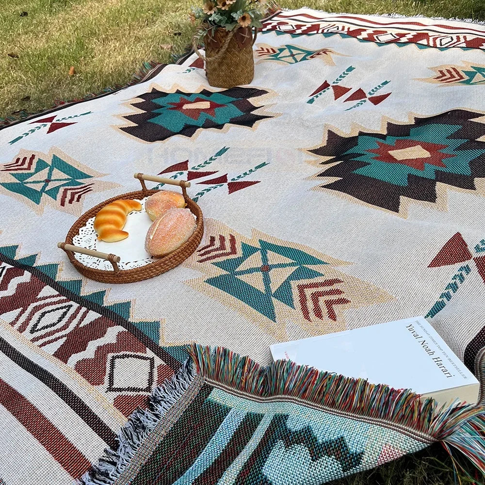 Geometric fringe throw blanket set up outdoors for a picnic with pastries and a book