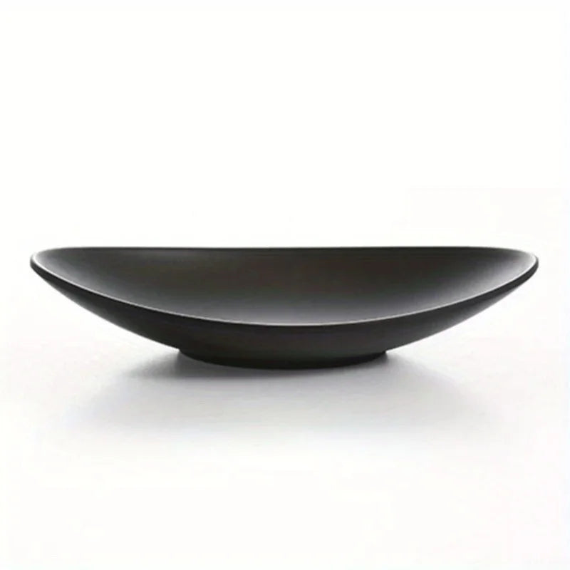 Side view of a matte black oval ceramic tray showing its curves