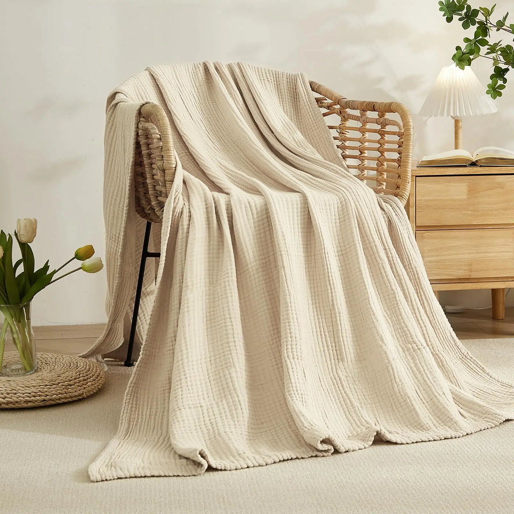 beige muslin blanket draped over a woven armchair in a cozy room